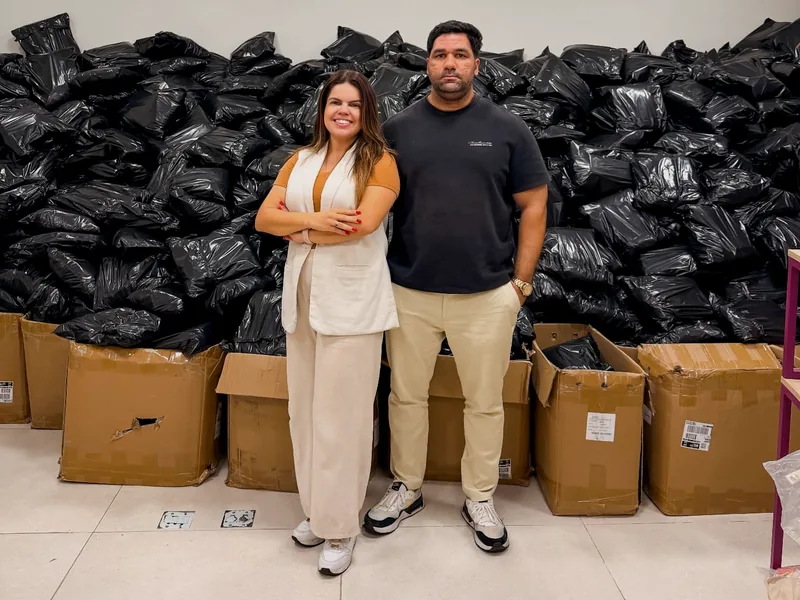 Luana Dias e Webert em frente ao volume de pedidos de fim de ano da gráfica